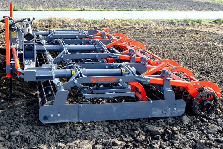 Vibroculteur Mandam gris et orange travaillant la terre pour affiner le sol en surface.