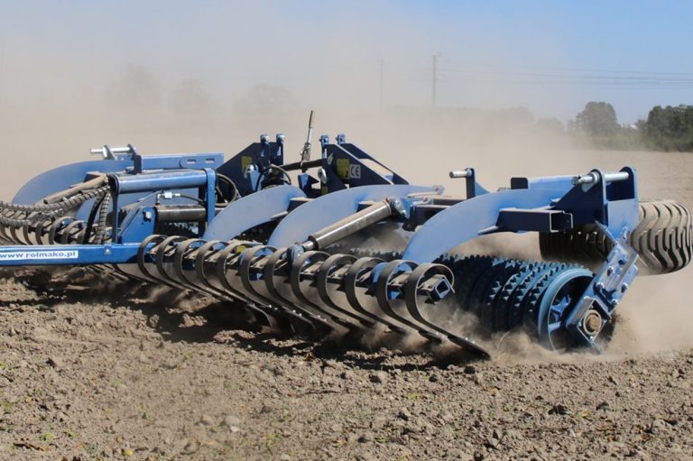 Rouleau lourd bleu Rolmako type Cambridge soulevant de la poussière au champ pour bloquer l'évaporation du sol.