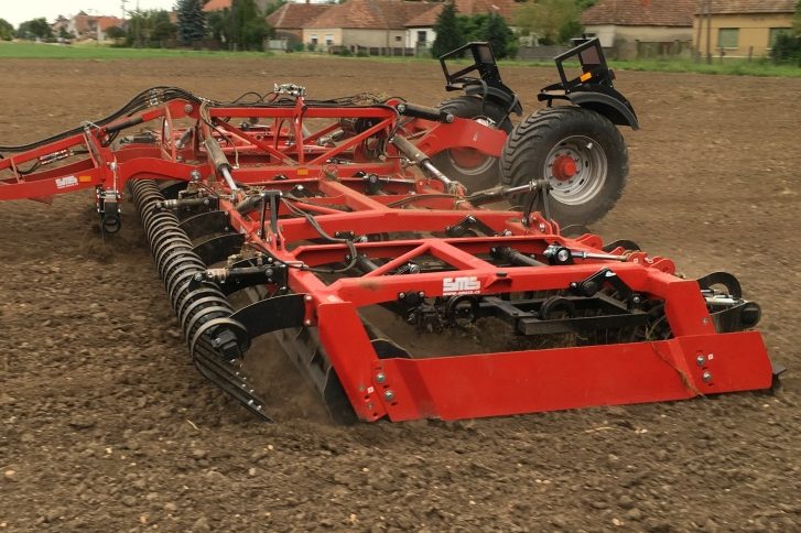 Vibroculteur rouge SMS Agro attelé au tracteur pour la préparation rapide et fine du lit de semence.