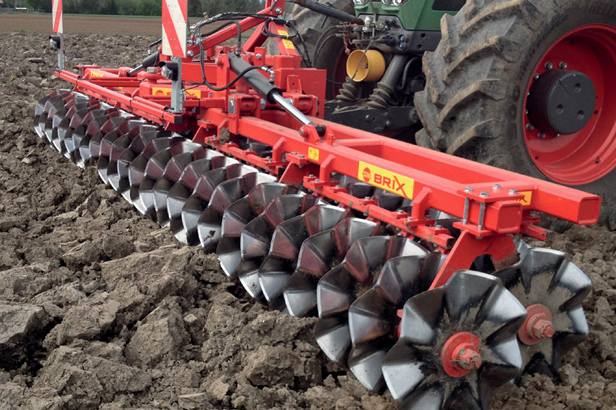 Outil frontal rouge Brix avec disques tranchants travaillant un sol motteux pour soulager l'outil arrière.