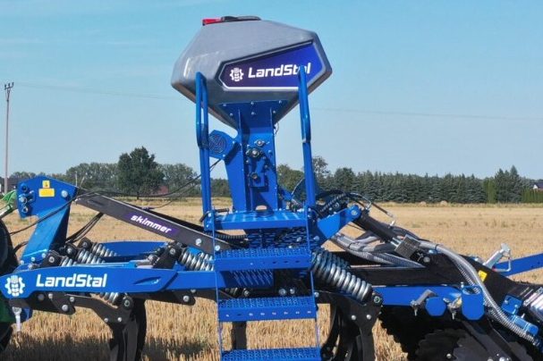 Trémie grise montée sur un outil de travail du sol bleu Landstal pour semer les couverts végétaux en un seul passage.