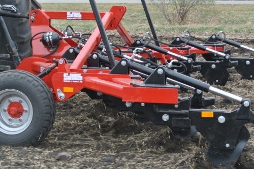 Machine de décompactage rouge et noire SMS Agro posée sur le sol.