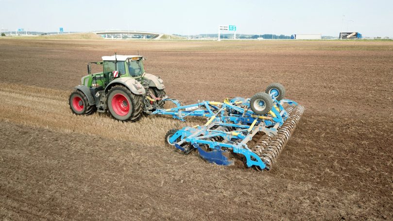 Tracteur attelé au déchaumeur à disques bleu Farmet Softer pour une préparation rapide et un nivellement parfait du lit de semence.