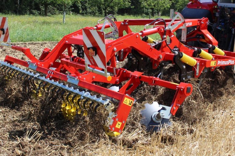Cultivateur agricole rouge et jaune Guttler en plein travail d'enfouissement des résidus.