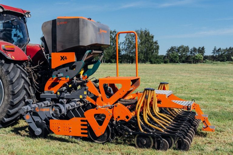 Semoir agricole orange et noir Mandam attelé à un tracteur pour un semis performant en conditions simplifiées.