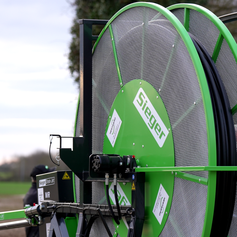 Enrouleur d'irrigation, vert, avec des bobines sur un terrain agricole. Déboucheuse à drains SIEGER DRAINJET WR avec ABS