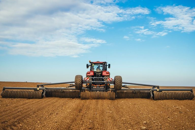 Très grand rouleau agricole gris et noir Mandam au travail dans une vaste plaine pour sécuriser les levées.