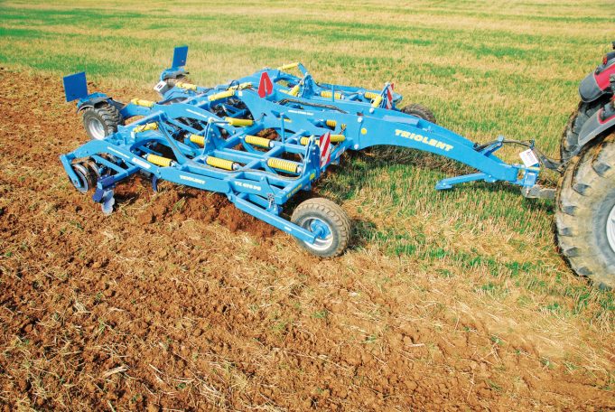 Cultivateur à dents bleu Farmet Triolent en action dans un champ pour un mélange profond et homogène des résidus végétaux.