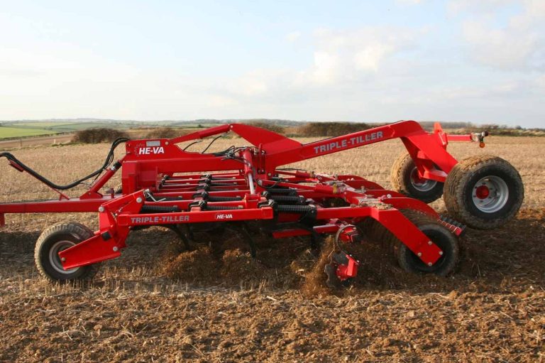 Déchaumeur à dents rouge HE-VA en action pour fissurer le sol sans retournement.