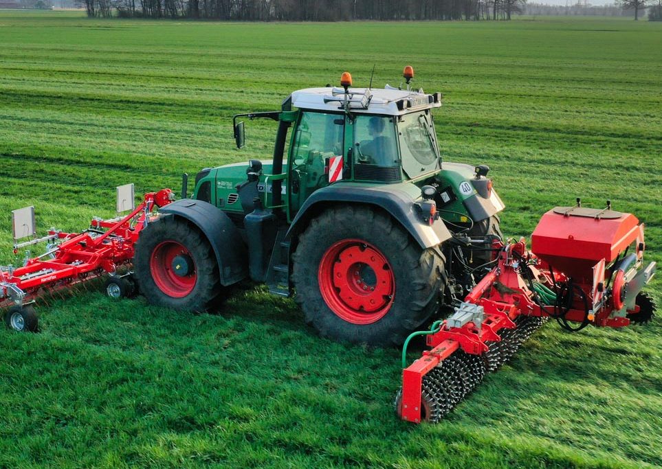Tracteur attelé à un combiné Guttler pour émousser, scarifier et regarnir les prairies en un seul passage.