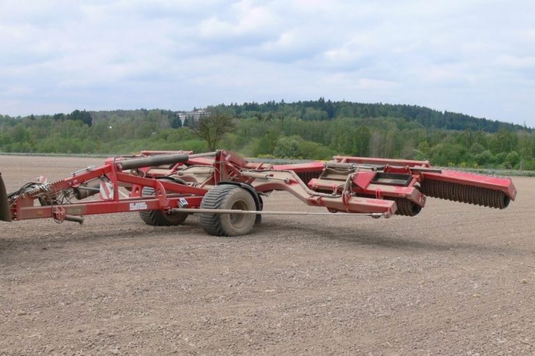 Rouleau agricole rouge SMS Agro stationné dans un champ, l'outil indispensable pour protéger vos semis.