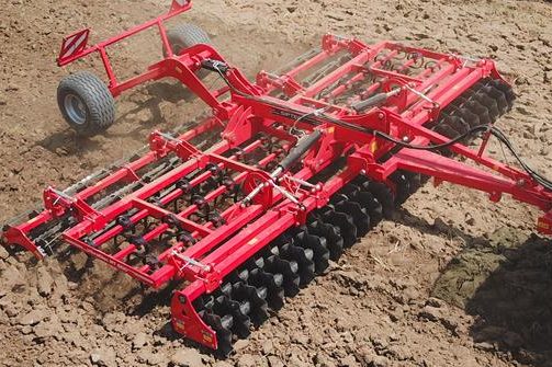 Préparateur de lit de semence rouge Siptec posé sur le sol, prêt pour les travaux de reprise.